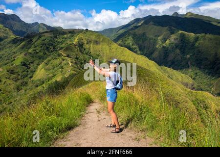 Une femme prend une photo sur son téléphone au sommet de la montagne. La femme tente de trouver le signal du téléphone. Recherche de connexion mobile dans la nature sauvage sur vac Banque D'Images