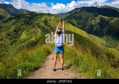 Une femme essaie de trouver un signal téléphonique dans les montagnes. Recherche de connexion mobile dans la nature sauvage en vacances. Parfait pour une journée à l'extérieur. Pas de communication Banque D'Images