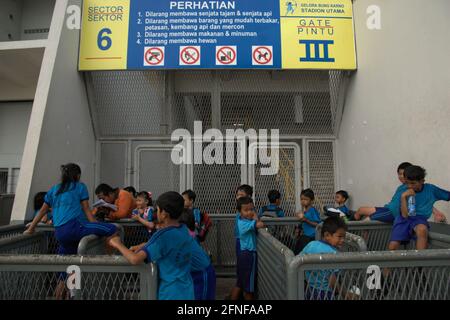 Un enseignant accompagne les élèves du primaire dans l'apprentissage en plein air après une séance de sport à l'extérieur du stade principal Senayan (stade Gelora Bung Karno) à Jakarta, en Indonésie. Banque D'Images