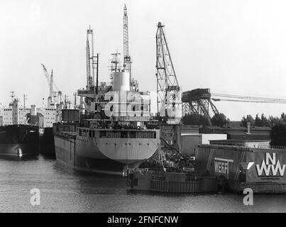 Un navire est déchargé avec des grues au chantier naval de Neptun Warnow à Rostock. Le port d'outre-mer de Rostock a été élargi entre 1957 et 1960 et des investissements ont été réalisés dans l'industrie des chantiers navals. [traduction automatique] Banque D'Images