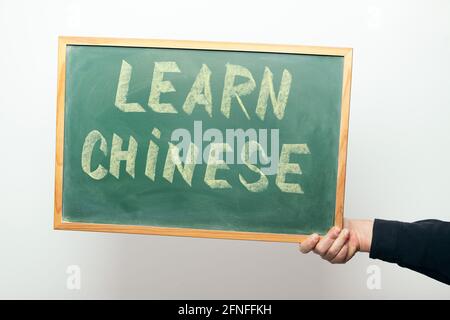 Main tenant un tableau avec le message APPRENDRE CHINOIS manuscrit à la craie Banque D'Images