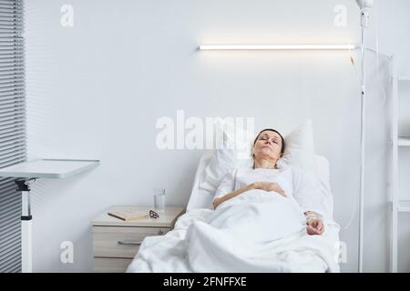 Femme sénior couché sur le lit après opération à l'hôpital Banque D'Images