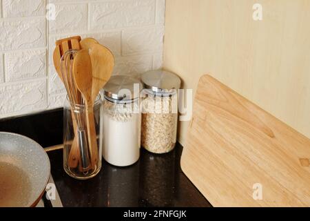 Bocaux avec farine et flocons d'avoine, fouet, spatules en bois et planche à découper sur le plan de travail de la cuisine Banque D'Images