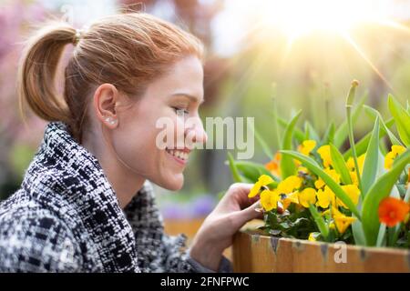 Bonne jeune femme blanche équilibrée à la recherche de fleurs dans le parc, profil vue portrait Banque D'Images