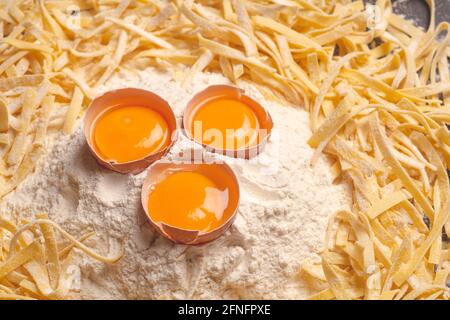 Fond de pâtes fraîches. Pâtes italiennes maison de fettuccine cuites dans la cuisine maison avec des œufs frais et de la farine sur un fond de bois. Cuisine italienne. Photo de haute qualité Banque D'Images