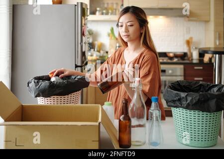 Jeune femme triant les déchets et le regroupement en différentes catégories à sa table de cuisine Banque D'Images