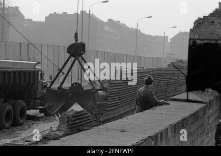 Berlin-City / GDR / 20.3.1980 Bernauer Strasse in Wedding. Les anciennes pierres murales sont remplacées par des éléments en forme de L en béton lisse. Le jeune garde-frontière est là pour surveiller les ouvriers de la construction. Pour les empêcher de fuir vers l'Occident. // RDA / mur / districts / Soldat / Histoire / communisme [traduction automatique] Banque D'Images