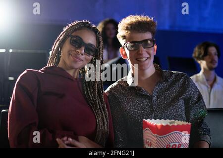 Jeune couple avec des lunettes 3d regardant un film au cinéma, regardant un appareil photo. Banque D'Images