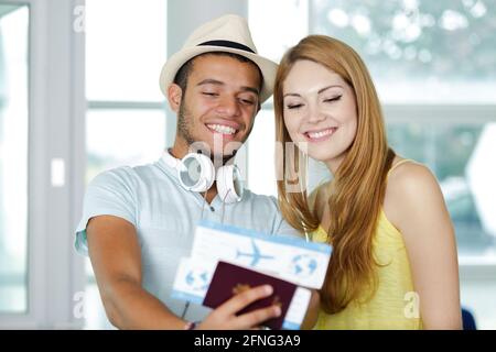 un jeune couple heureux qui détient un passeport et des billets d'avion Banque D'Images
