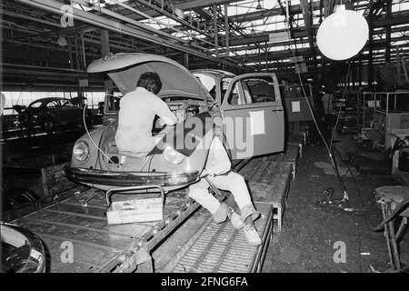 Deux mécaniciens travaillent sur un Beetle à l'usine VW de Puebla. [traduction automatique] Banque D'Images