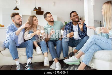 Groupe d'amis du millénaire heureux qui boivent du thé, qui parlent, qui apprécient le temps ensemble à la maison Banque D'Images