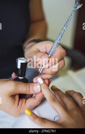 Par-dessus la récolte manucuriste méconnaissable faisant l'art des ongles pour femme dans le salon de beauté en plein jour Banque D'Images