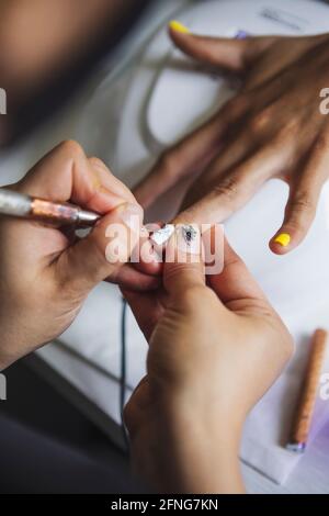 Par-dessus la récolte manucuriste méconnaissable faisant l'art des ongles pour femme dans le salon de beauté en plein jour Banque D'Images