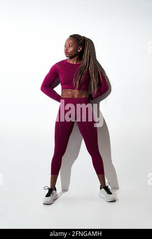 Jeune athlète féminine de sport et de baskets debout avec les mains derrière le dos tout en regardant loin Banque D'Images