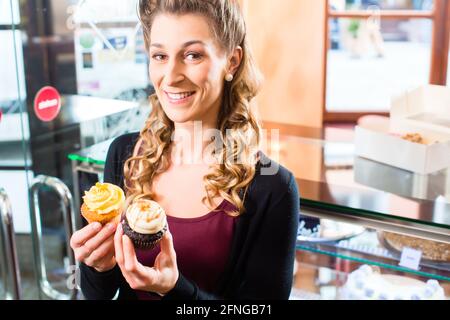 Femme présentant des muffins et cupcakes en boulangerie ou pâtisserie Banque D'Images