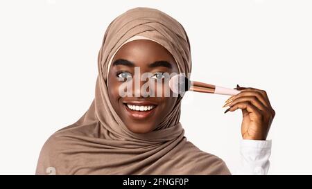 Portrait d'une belle femme noire musulmane avec pinceau à maquillage Banque D'Images