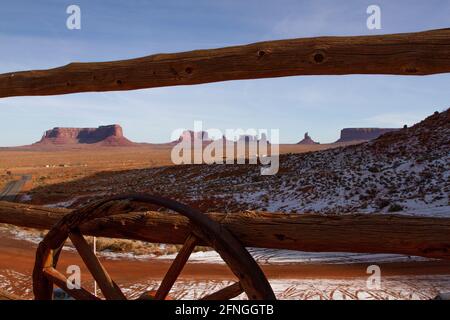 Monument Valley en hiver à travers une clôture en bois avec des roues de stagecoach de Gouldings Lodge, Arizona Banque D'Images