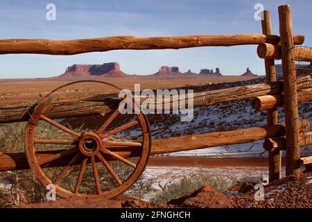 Monument Valley en hiver à travers une clôture en bois avec des roues de stagecoach de Gouldings Lodge, Arizona Banque D'Images