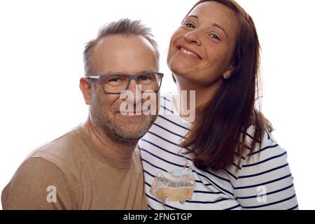 Souriant sympathique décontracté affectueux couple d'âge moyen posant avec leurs bras les uns autour des autres en regardant la caméra isolée sur blanc Banque D'Images