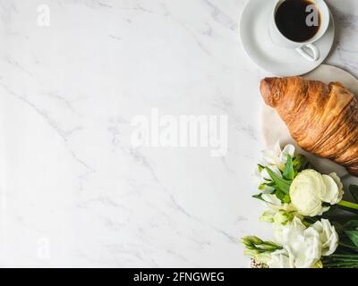 Cadre plat de présentation de tasses de café, bouquet de fleurs et croissant sur fond de marbre. Concept petit déjeuner français. Vue de dessus. Copier l'espace Banque D'Images