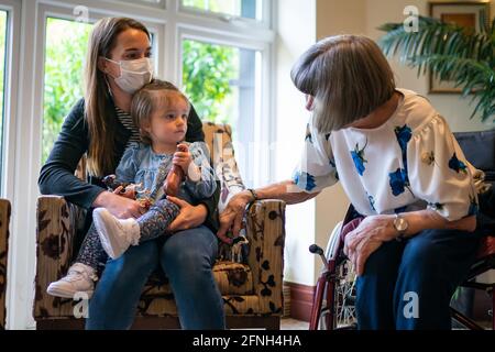 RETRANSMETTANT L'ORTHOGRAPHE DU NOM DE MIA À MYA LÉGENDE CORRECTE CI-DESSOUS Pat Tinner 79 (à droite) rencontre sa petite-fille Kimberley Skelton et sa grande petite-fille Mya (18 mois) pour la première fois depuis Noël à la maison de soins Sunrise of Bagshot à Bagshot, Surrey, les règles de verrouillage du coronavirus sont assouplies pour les résidents des foyers de soins. À partir de lundi, les résidents peuvent avoir jusqu'à cinq visiteurs désignés et peuvent aller sur plus de visites sans avoir besoin de s'isoler par la suite. Date de la photo: Lundi 17 mai 2021. Banque D'Images