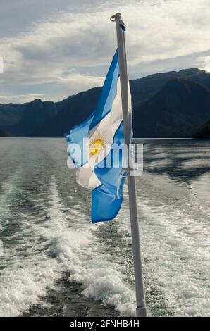 Premier plan, bleu clair et blanc drapeau argentin fait de tissu sur un bateau, avec une trace d'eau du lac Nahuel Huapi en arrière-plan Banque D'Images