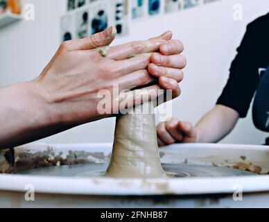 De belles mains de femmes au-dessus de la roue de potier. Sculptez de l'argile dans un atelier de poterie. Poterie traditionnelle. Concept d'atelier de céramique Banque D'Images