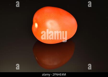 Une tomate rouge, gros plan, sur fond noir. Banque D'Images