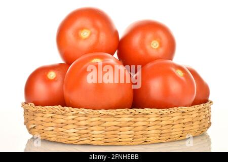 Plusieurs tomates juteuses rouge vif avec une assiette de paille, gros plan, sur fond blanc. Banque D'Images