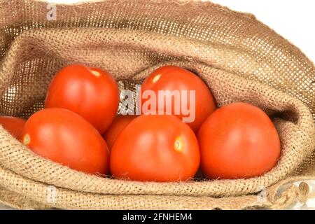 Plusieurs tomates juteuses rouge vif dans un sac de jute, gros plan. Banque D'Images