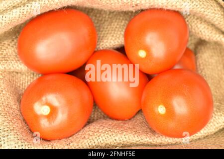 Plusieurs tomates rouges mûres dans un sac de jute, gros plan. Banque D'Images