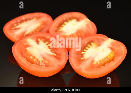 Quatre moitiés de tomates rouges, gros plan, sur fond noir. Banque D'Images