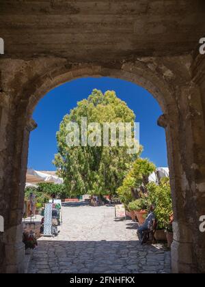 Scopello, Trapani, Sicile, Italie. Vue à travers l'arche de pierre marquant l'entrée de cour ensoleillée de l'ancien baglio. Banque D'Images