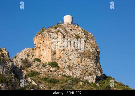 Scopello, Trapani, Sicile, Italie. Vue à angle bas de la vallée à la Torre Bennistra, une tour de guet médiévale restaurée, aujourd'hui un mirador au sommet d'une falaise. Banque D'Images