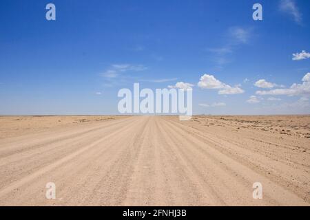 La randonnée pédestre de l'autoroute vide route poussiéreuse pas de gens qui frappent la route Damaraland, Namibie. Banque D'Images