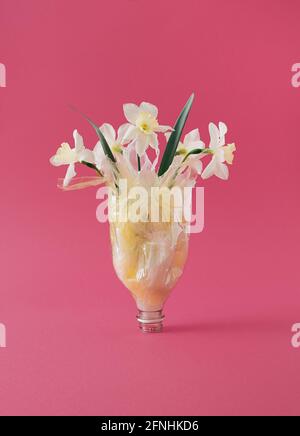 Fleurs disposées dans une bouteille en plastique comme un vase pour les déchets recyclés concept d'art Banque D'Images