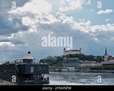 Le château de Bratislava s’élève au-dessus du Danube alors que les rayons du soleil traversent les nuages au-dessus de la capitale slovaque. Banque D'Images