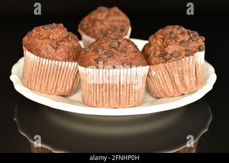 Quelques délicieux muffins au chocolat sur une assiette, gros plan, sur fond noir. Banque D'Images