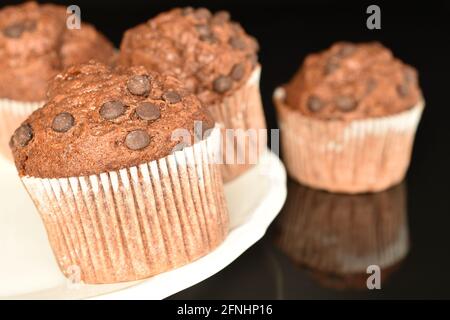 Quelques délicieux muffins au chocolat sur une assiette, gros plan, sur fond noir. Banque D'Images