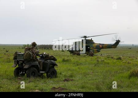 Un soldat néerlandais affecté au 11e Bataillon aéroporté observe comme soldats de la Force opérationnelle Falcon se préparer à charger dans un hélicoptère Puma roumain pendant l'exercice Swift Response 21 à la zone d'entraînement de Babadag, le 16 mai 2021 à Babadag, Roumanie. Banque D'Images