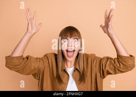 Photo de la jeune dame gaie étonnée lever les mains choqué rabais shopping isolé sur fond de couleur beige pastel Banque D'Images