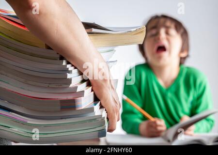 Un rôle parental ambitieux avec des attentes élevées de réussite scolaire de la part des enfants concept. Une mère apporte une pile de livres de préparation aux tests à sa lasse, fatiguée Banque D'Images