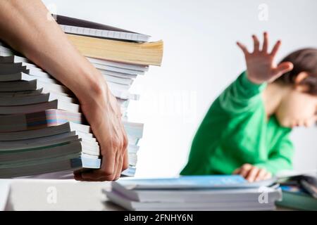 Un rôle parental ambitieux avec des attentes élevées de réussite scolaire de la part des enfants concept. Une mère apporte une pile de livres de préparation aux tests à sa lasse, fatiguée Banque D'Images