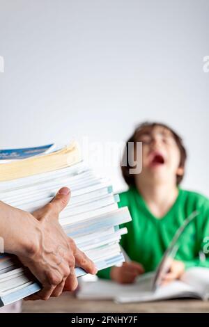 Un rôle parental ambitieux avec des attentes élevées de réussite scolaire de la part des enfants concept. Une mère apporte une pile de livres de préparation aux tests à sa lasse, fatiguée Banque D'Images