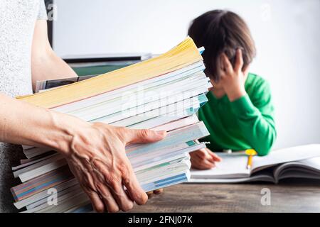 Un rôle parental ambitieux avec des attentes élevées de réussite scolaire de la part des enfants concept. Une mère apporte une pile de livres de préparation aux tests à sa lasse, fatiguée Banque D'Images