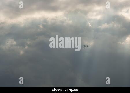 Image couleur de deux avions Spitfire en formation haut dans le ciel et tenu dans un faisceau de lumière du soleil contre des nuages beaucoup plus sombres Banque D'Images