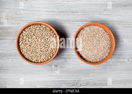 vue de dessus de grains de seigle entiers et écrasés en rond bols en céramique sur table en bois gris Banque D'Images