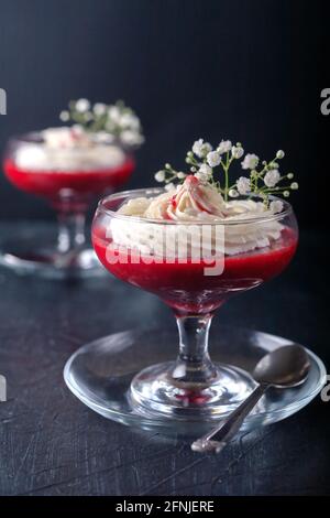 Dessert framboise-fraise avec crème au fromage dans de la verrine sur un noir arrière-plan Banque D'Images