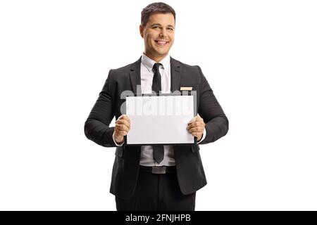 Homme en costume et cravate tenant une planche vide sur arrivées isolées sur fond blanc Banque D'Images