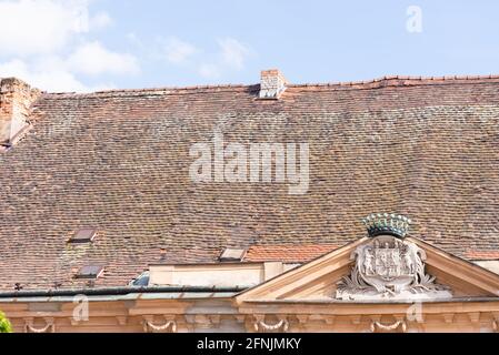 Le toit est fait de carreaux d'argile. Ancien toit d'un bâtiment médiéval à Bratislava avec les armoiries sur le pignon. Banque D'Images